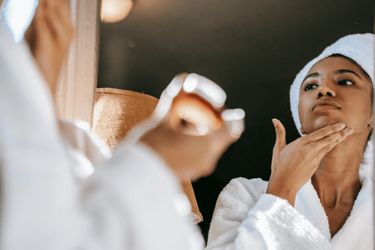 Woman applying face cream and looking in the mirror